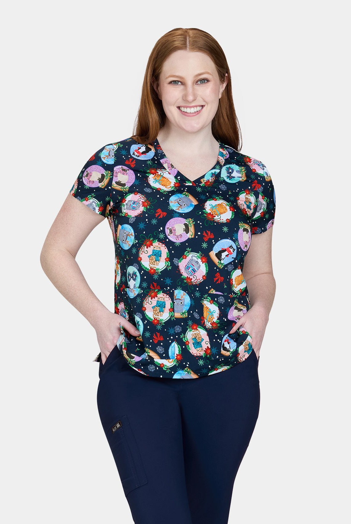 Woman wearing Koi Basics Leslie scrub top with colourful holiday cat print.